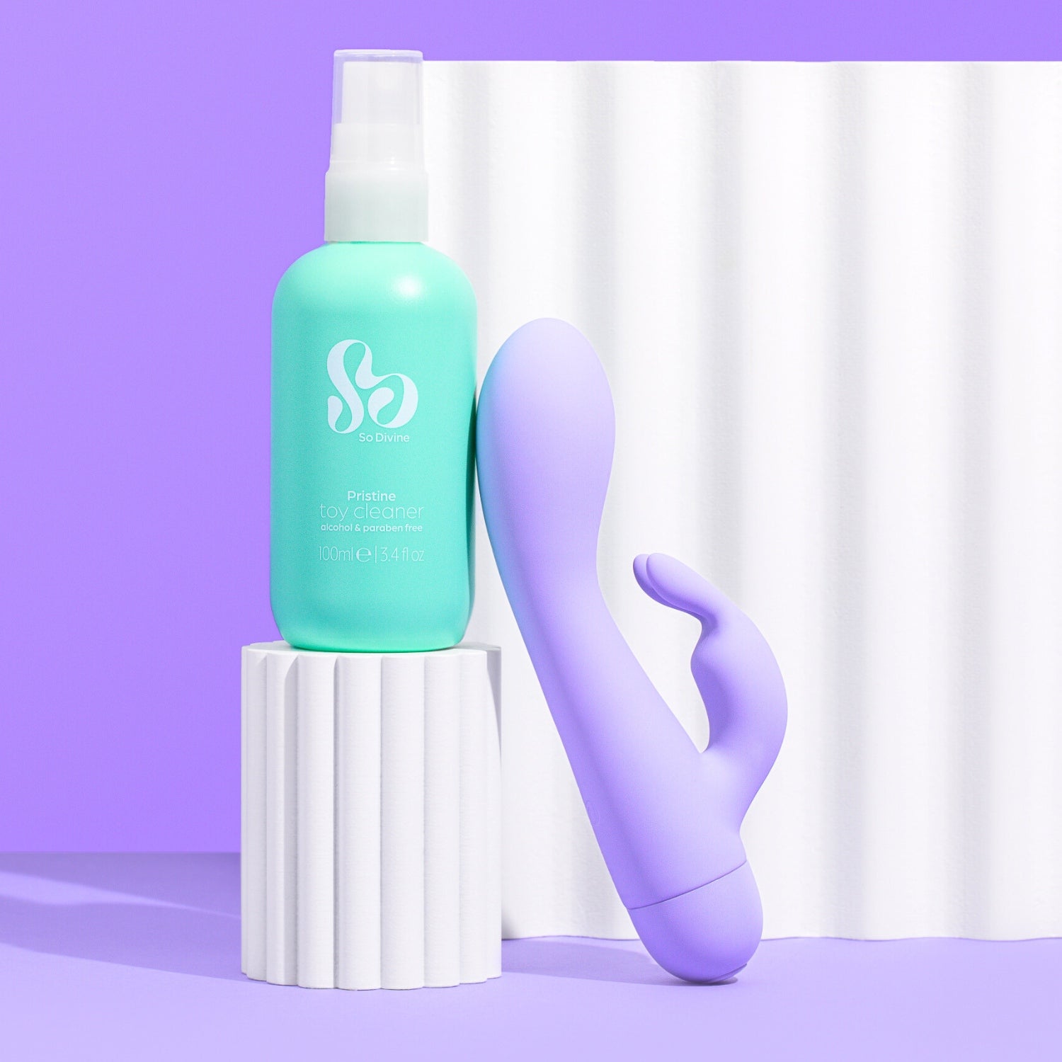 So Divine Pristine Sex Toy Cleaning Spray in a green bottle, placed next to the So Divine Pearl Rabbit Vibrator 